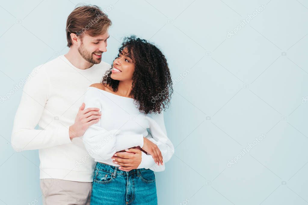 Smiling beautiful woman and her handsome boyfriend. Happy cheerful multiracial family having tender moments on grey background  in studio. Multiethnic models hugging. Embracing each other.Love concept