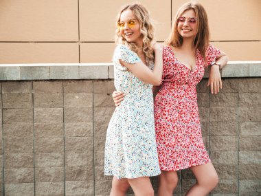 İki güzel, güler yüzlü yeniyetme kadın, son moda yaz kıyafetleri içinde. Sokakta poz veren kaygısız kadınlar. Pozitif modeller eğleniyor ve sarılıyorlar.