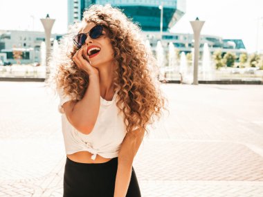 Kıvırcık saçlı, yaz hippi kıyafetleri giymiş güzel bir mankenin portresi. Sokakta poz veren tasasız bir model. Modayı takip eden eğlenceli ve olumlu kadın.