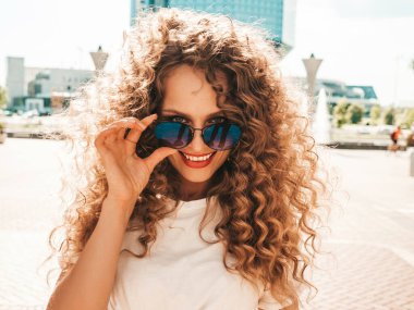 Kıvırcık saçlı, yaz hippi kıyafetleri giymiş güzel bir mankenin portresi. Sokakta poz veren tasasız bir model. Modayı takip eden eğlenceli ve olumlu kadın.