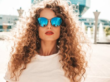 Kıvırcık saçlı, yaz hippi kıyafetleri giymiş güzel bir mankenin portresi. Sokakta poz veren tasasız bir model. Modayı takip eden eğlenceli ve olumlu kadın.