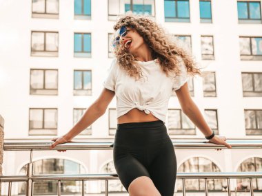 Kıvırcık saçlı, yaz hippi kıyafetleri giymiş güzel bir mankenin portresi. Sokakta poz veren tasasız bir model. Modayı takip eden eğlenceli ve olumlu kadın.