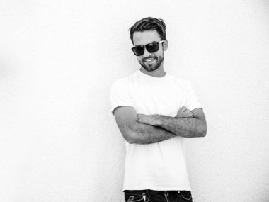 Yakışıklı, kendine güvenen, stil sahibi, Lambersex mankeni portresi. Beyaz tişört giyen adam. Moda erkeği güneş gözlükleriyle sokakta poz veriyor. Çapraz kollar. Siyah ve beyaz