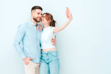 Gülümseyen güzel kadın ve yakışıklı erkek arkadaşı. Mutlu mutlu aile stüdyoda açık mavi duvarın yanında hassas anlar yaşıyor. Saf, neşeli modeller sarılıyor. Birbirlerine sarılıyorlar.