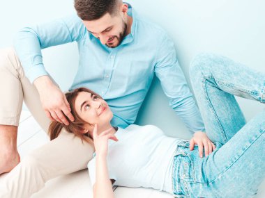 Gülümseyen güzel kadın ve yakışıklı erkek arkadaşı. Mutlu mutlu aile stüdyoda açık mavi duvarın yanında hassas anlar yaşıyor. Saf, neşeli kadın erkeğinin kucağında yatıyor.