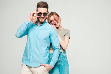 Gülümseyen güzel kadın ve yakışıklı erkek arkadaşı. Mutlu, neşeli bir aile stüdyodaki gri arka planda hassas anlar yaşıyor. Saf, neşeli modeller sarılıyor. Güneş gözlükleriyle birbirlerine sarılıyorlar. 