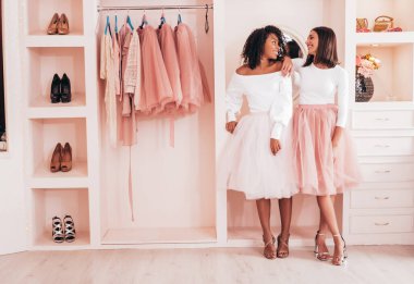 Son moda yaz elbiseleri içinde gülümseyen iki güzel uluslararası hippi kadın. Pembe gardıropta poz veren kaygısız seksi kadınlar. Pozitif modeller eğleniyor. Arkadaşlık kavramı 