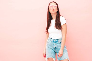 Yeni moda hippi kıyafetleri içinde gülümseyen güzel bir kadın. Stüdyoda pembe duvarın yanında poz veren kaygısız seksi kadın. Pozitif model içeride eğleniyor. Neşeli ve mutlu