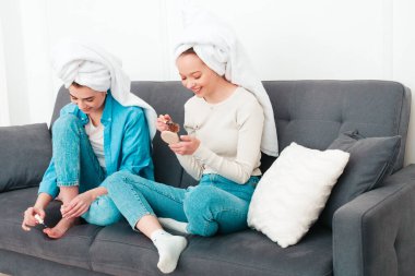 İki güzel, güzel, gülümseyen kadın lüks bir dairede ya da otel odasında poz veren kaygısız mankenler. Makyaj yapıyor, kafalarına havlu takıyor ve tırnaklarını ojeyle boyuyorlar.