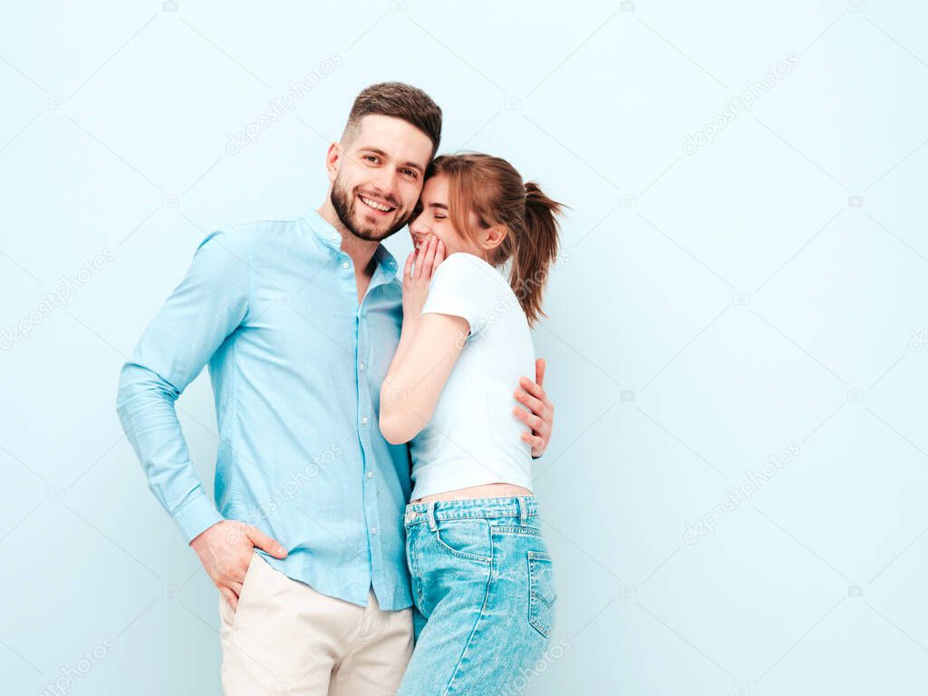 Smiling beautiful woman and her handsome boyfriend. Happy cheerful family having tender moments near light blue wall in studio.Pure cheerful models hugging.Embracing each other