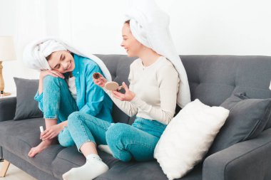 İki güzel, güzel, gülümseyen kadın lüks bir dairede ya da otel odasında poz veren kaygısız mankenler. Makyaj yapıyor, kafalarına havlu takıyor ve tırnaklarını ojeyle boyuyorlar.