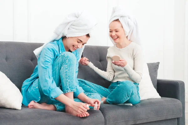 İki güzel, güzel, gülümseyen kadın lüks bir dairede ya da otel odasında poz veren kaygısız mankenler. Makyaj yapıyor, kafalarına havlu takıyor ve tırnaklarını ojeyle boyuyorlar.