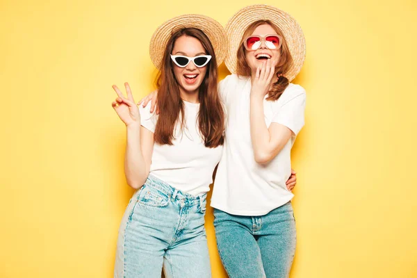 两个年轻美丽的嬉皮士女 穿着时髦的夏季白衬衫和牛仔裤衣服 穿着时髦的无忧无虑的女人在黄墙边摆姿势学习 — 图库照片
