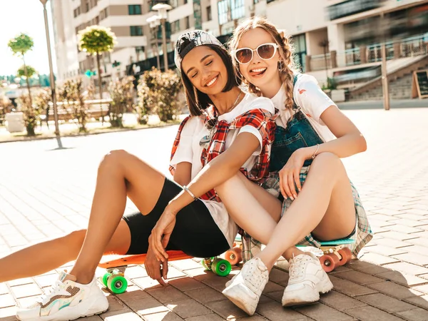 カラフルなペニースケートボードを持つ2人の若い笑顔の美しい女性 通りの背景に座って夏のヒップスター服の女性 正のモデルは楽しさとクレイジー行く — ストック写真