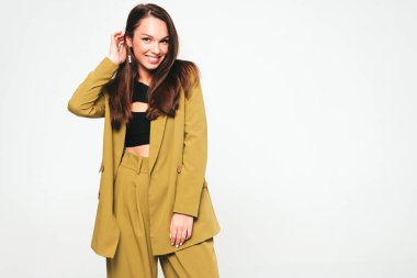 Moda kıyafetleri içinde gülümseyen genç ve güzel bir bayan. Stüdyoda gri arka planda poz veren kaygısız seksi kadın. Pozitif model içeride eğleniyor. Neşeli ve mutlu