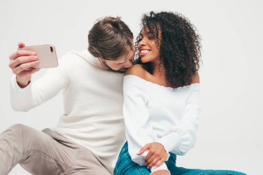 Gülümseyen güzel kadın ve yakışıklı erkek arkadaşı. Mutlu çok ırklı aile, gri arka planda hassas anlar yaşıyor. Çok ırklı modeller sarılıyor. Birbirlerine sarılıyorlar. Selfie çekiyorlar.