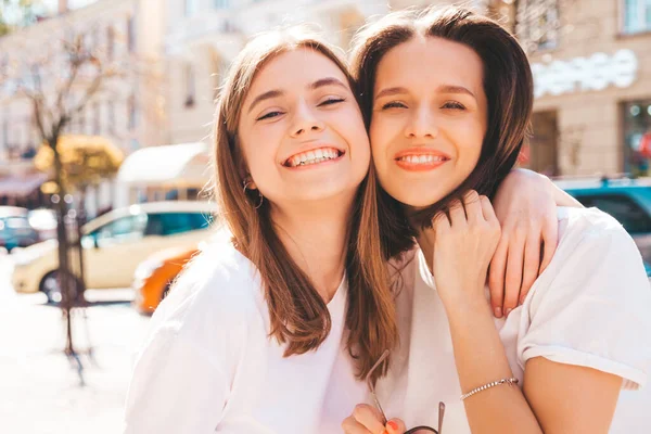 两个年轻美丽的嬉皮士女 穿着时髦的夏季白色T恤衫和牛仔裤 穿着无忧无虑的性感女人在街上摆姿势 拥抱和发疯的正面模特 — 图库照片