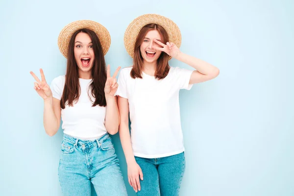 两个年轻美丽的嬉皮士女 穿着时髦的夏季白衬衫和牛仔裤衣服 性感无忧无虑的女人穿着浅蓝色的墙壁在学习 — 图库照片