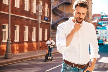 Yakışıklı, kendine güvenen, stil sahibi, Lambersex mankeni portresi. Beyaz gömlek giymiş modern bir adam. Moda erkeği sokakta poz veriyor. Gün batımında dışarıda. 