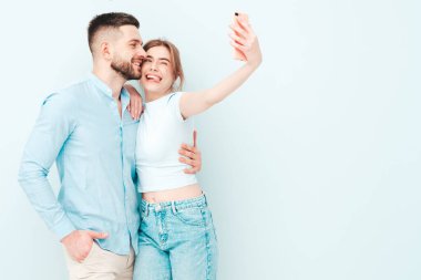 Gülümseyen güzel kadın ve yakışıklı erkek arkadaşı. Mutlu mutlu aile stüdyoda açık mavi duvarın yanında hassas anlar yaşıyor. Saf, neşeli modeller sarılıyor. Birbirlerine sarılıyorlar.