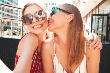 Son moda yaz kıyafetleri içinde iki güzel gülümseyen yeniyetme kadın. Sokakta Veranda Kafe 'de poz veren kaygısız kadınlar. Pozitif modeller eğleniyor ve akıllı telefondan Pov selfie çekiyor.