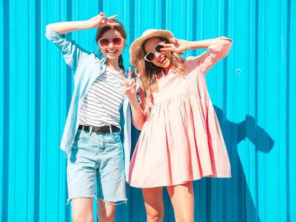 两个年轻美丽的嬉皮士女 穿着时髦的夏装 穿着时髦的夏装 性感无忧无虑的女人在蓝色墙边的街上摆姿势 — 图库照片