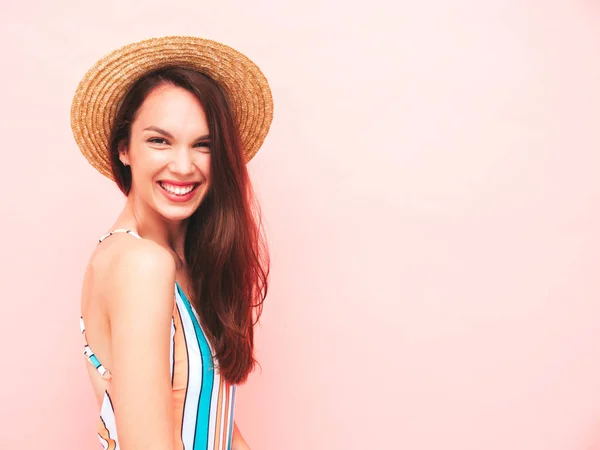 スタジオでピンクの壁の近くにポーズで若い美しいセクシーな笑顔ヒップスター女性 カラフルな夏の水着水着のトレンドモデル 肯定的なモデルはクレイジーになります 帽子で幸せと陽気 — ストック写真