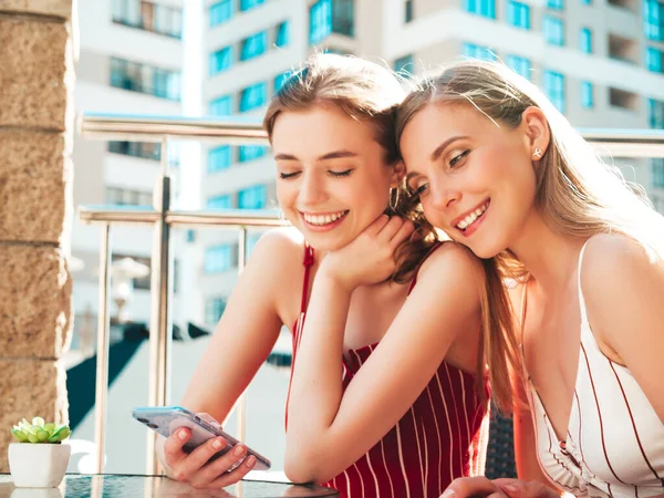 流行の夏の全体で2人の若い美しい笑顔のヒップスター女性 ベランダカフェでおしゃべり介護無料の女性 モデルは 彼女のスマートフォンで彼女の友人情報を示しています — ストック写真