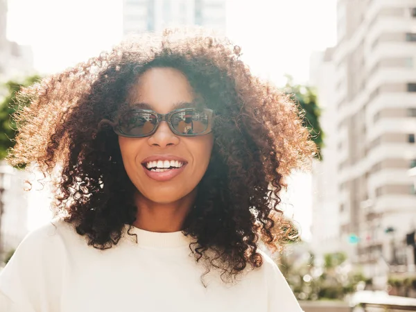 Beautiful black woman with an afro hairstyle wear white bra and blue jeans  looking at camera and smiling Stock Photo