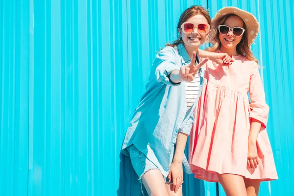 两个年轻美丽的嬉皮士女 穿着时髦的夏装 穿着时髦的夏装 性感无忧无虑的女人在蓝色墙边的街上摆姿势 — 图库照片