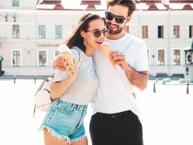 Gülümseyen güzel kadın ve yakışıklı erkek arkadaşı. Gündelik yaz kıyafetleri giymiş bir kadın. Mutlu, neşeli bir aile. Sokakta güneş gözlüklü bir çift poz veriyor. Waffle külahında lezzetli dondurma yemek.
