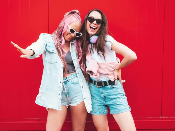 两个年轻美丽的嬉皮士女 穿着时髦的夏装 性感无忧无虑的女人在红墙边的街上摆姿势 一头粉红的头发 很有乐趣的纯模特 快乐而快乐 — 图库照片