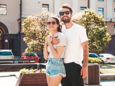 Gülümseyen güzel kadın ve yakışıklı erkek arkadaşı. Gündelik yaz kıyafetleri giymiş bir kadın. Mutlu, neşeli bir aile. Kadın eğleniyor. Güneş gözlükleriyle sokakta poz veren çift. Birbirlerine sarılıyorlar.