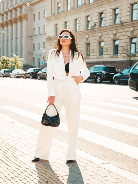 若いセクシーな現代的なビジネスウーマンモデルの肖像 通りの背景にポーズを白のスーツで熱い美しい女性 サングラスで屋外を歩くファッション女性 — ストック写真