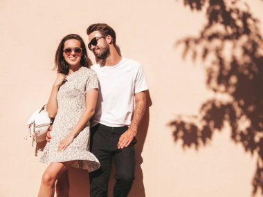 Gülümseyen güzel bir kadın ve yakışıklı erkek arkadaşının portresi. Gündelik yaz kıyafetleri giymiş bir kadın. Mutlu, neşeli bir aile. Kadın eğleniyor. Sokağın kenarında güneş gözlüklü bir çift poz veriyor.