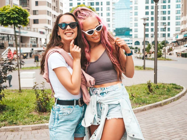 流行の夏服で2人の若い美しい笑顔のヒップスター女性 ピンクの髪で通りにポーズ性的屈託のない女性 正の純粋なモデルは 日没で楽しんでいます 陽気で幸せ — ストック写真