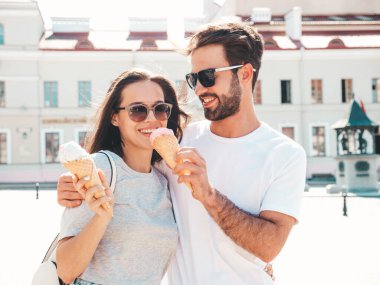 Gülümseyen güzel kadın ve yakışıklı erkek arkadaşı. Gündelik yaz kıyafetleri giymiş bir kadın. Mutlu, neşeli bir aile. Sokakta güneş gözlüklü bir çift poz veriyor. Waffle külahında lezzetli dondurma yemek.