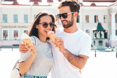 Gülümseyen güzel kadın ve yakışıklı erkek arkadaşı. Gündelik yaz kıyafetleri giymiş bir kadın. Mutlu, neşeli bir aile. Sokakta güneş gözlüklü bir çift poz veriyor. Waffle külahında lezzetli dondurma yemek.