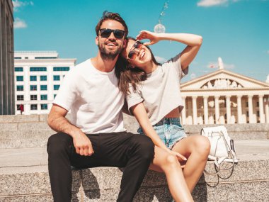 Gülümseyen güzel bir kadın ve yakışıklı erkek arkadaşının portresi. Gündelik yaz kıyafetleri giymiş bir kadın. Mutlu, neşeli bir aile. Kadın eğleniyor. Güneş gözlüklü bir çift sokakta poz veriyor.