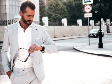 Yakışıklı, kendine güvenen, havalı, havalı, Lambersex mankeni. Zarif beyaz takım elbiseli adam. Moda erkeği gün batımında Avrupa şehrinin arka planında poz veriyor. Güneş gözlükleriyle