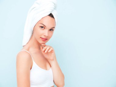 Beyaz iç çamaşırlı, gülümseyen genç bir kadın. Stüdyoda açık mavi duvarın yanında duran iç çamaşırlı ve kafasında havlu olan seksi tasasız manken. Olumlu ve mutlu bir kadın Sabahın tadını çıkarıyor