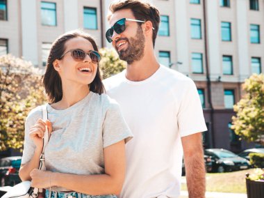 Gülümseyen güzel kadın ve yakışıklı erkek arkadaşı. Gündelik yaz kıyafetleri giymiş bir kadın. Mutlu, neşeli bir aile. Kadın eğleniyor. Güneş gözlükleriyle sokakta poz veren çift. Birbirlerine sarılıyorlar.
