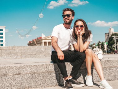 Gülümseyen güzel bir kadın ve yakışıklı erkek arkadaşının portresi. Gündelik yaz kıyafetleri giymiş bir kadın. Mutlu, neşeli bir aile. Kadın eğleniyor. Güneş gözlüklü bir çift sokakta poz veriyor.