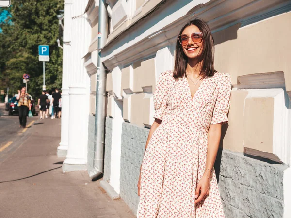 Modayı takip eden yaz elbisesi giymiş güzel, gülümseyen hippi kadın. Günbatımında sokakta poz veren kaygısız seksi kadın. Güneş gözlüklü, açık hava modeli. Neşeli ve mutlu 