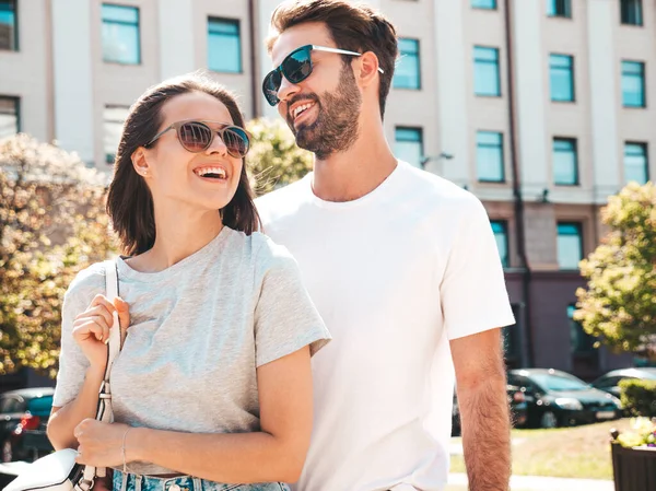 Gülümseyen güzel kadın ve yakışıklı erkek arkadaşı. Gündelik yaz kıyafetleri giymiş bir kadın. Mutlu, neşeli bir aile. Kadın eğleniyor. Güneş gözlükleriyle sokakta poz veren çift. Birbirlerine sarılıyorlar.