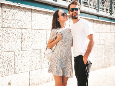 Gülümseyen güzel kadın ve yakışıklı erkek arkadaşı. Gündelik yaz kıyafetleri giymiş bir kadın. Mutlu, neşeli bir aile. Kadın eğleniyor. Güneş gözlükleriyle sokakta poz veren çift. Birbirlerine sarılıyorlar.