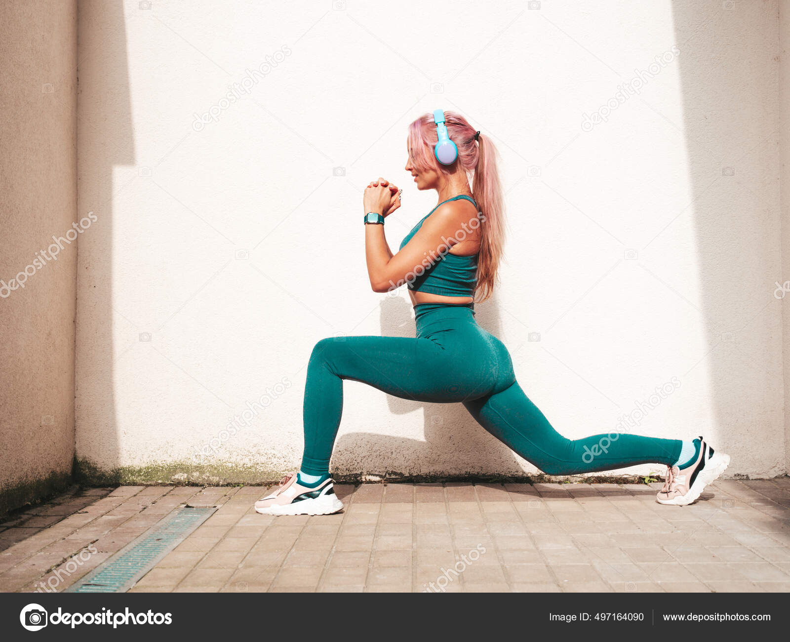 Fitness mujer sonriente en ropa deportiva verde con cabello rosado