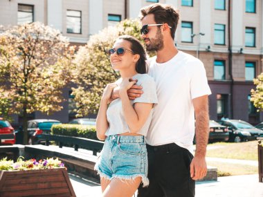 Gülümseyen güzel kadın ve yakışıklı erkek arkadaşı. Gündelik yaz kıyafetleri giymiş bir kadın. Mutlu, neşeli bir aile. Kadın eğleniyor. Güneş gözlükleriyle sokakta poz veren çift. Birbirlerine sarılıyorlar.