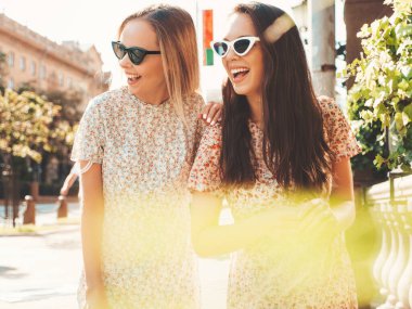 Son moda yaz kıyafetleri içinde iki güzel gülümseyen hippi kadın. Sokakta poz veren kaygısız kadınlar. Pozitif saf modeller gün batımında eğleniyor, sarılıyor ve deliriyor. Mutlu ve neşeli.
