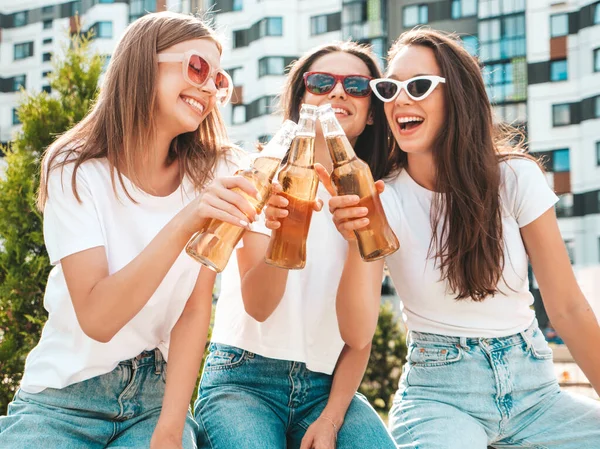 Üç güzel, güler yüzlü yeniyetme kadın aynı yaz kıyafetleri içinde. Sokakta poz veren kaygısız kadınlar. Güneş gözlükleriyle eğlenen pozitif modeller. Şişe bira içmek. Ekim Festivali